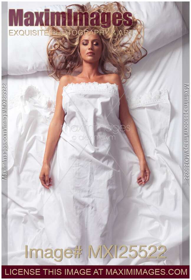 Beautiful woman with long blond hair sleeping on white bed sheets