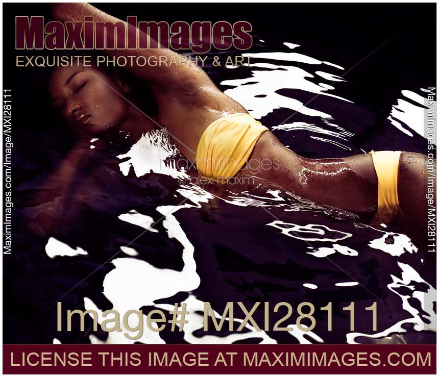 African american woman in bikini lying in black water