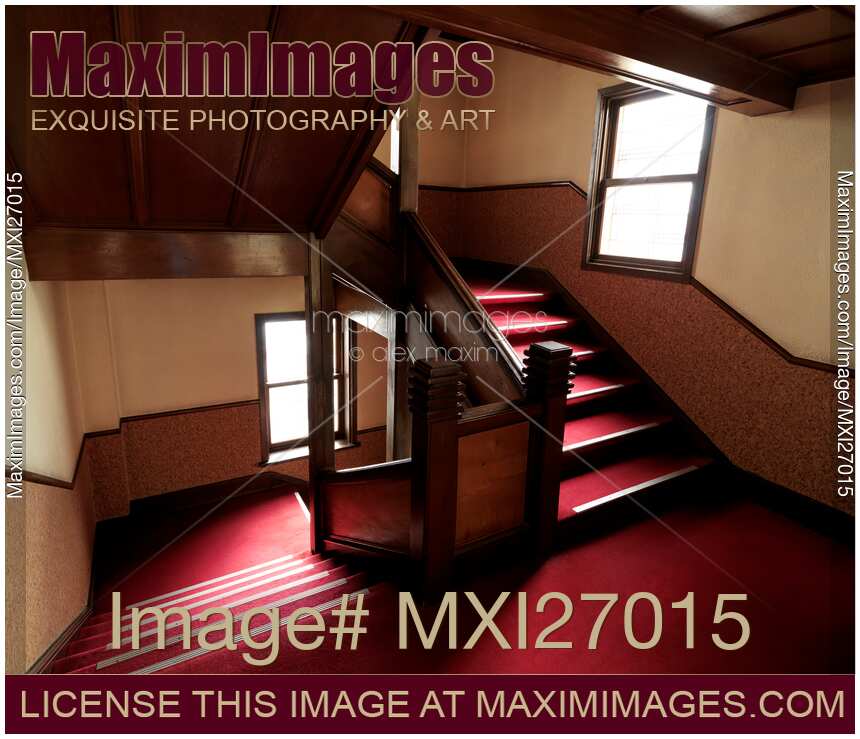 Antique wooden staircase with red carpet