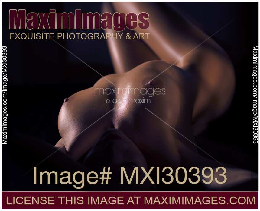 Art nude sexy woman lying in dark with her body lit by dim light closeup of breast with oily skin