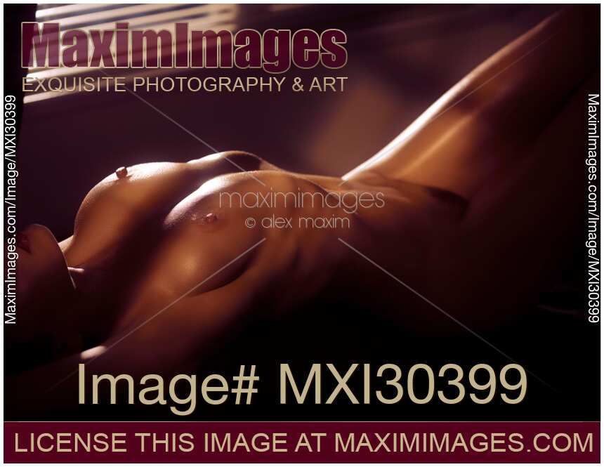 Art nude sexy woman lying with her naked body outline lit by dim night light and hidden by shadows
