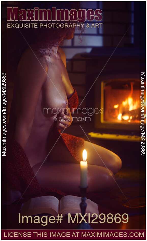 Artistic erotic portrait of beautiful sexy woman sitting naked by the fireplace with a book