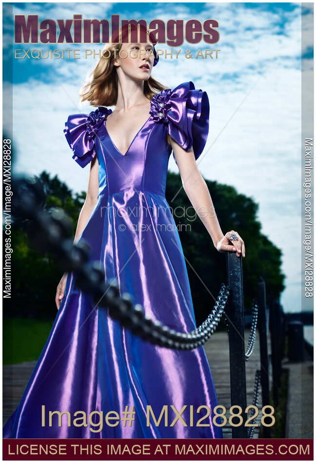 Artistic fashion portrait of woman in beautiful long blue dress at a pier