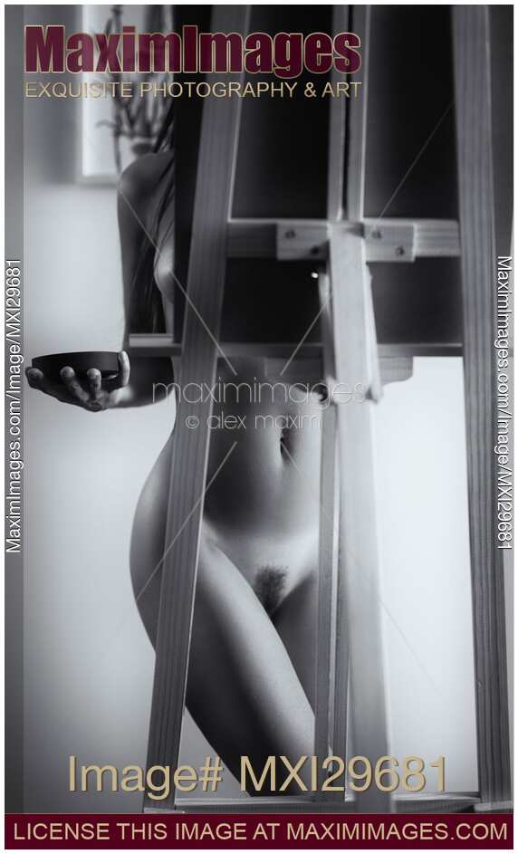 Artistic nude black and white portrait of young woman artist with easel painting naked in her studio