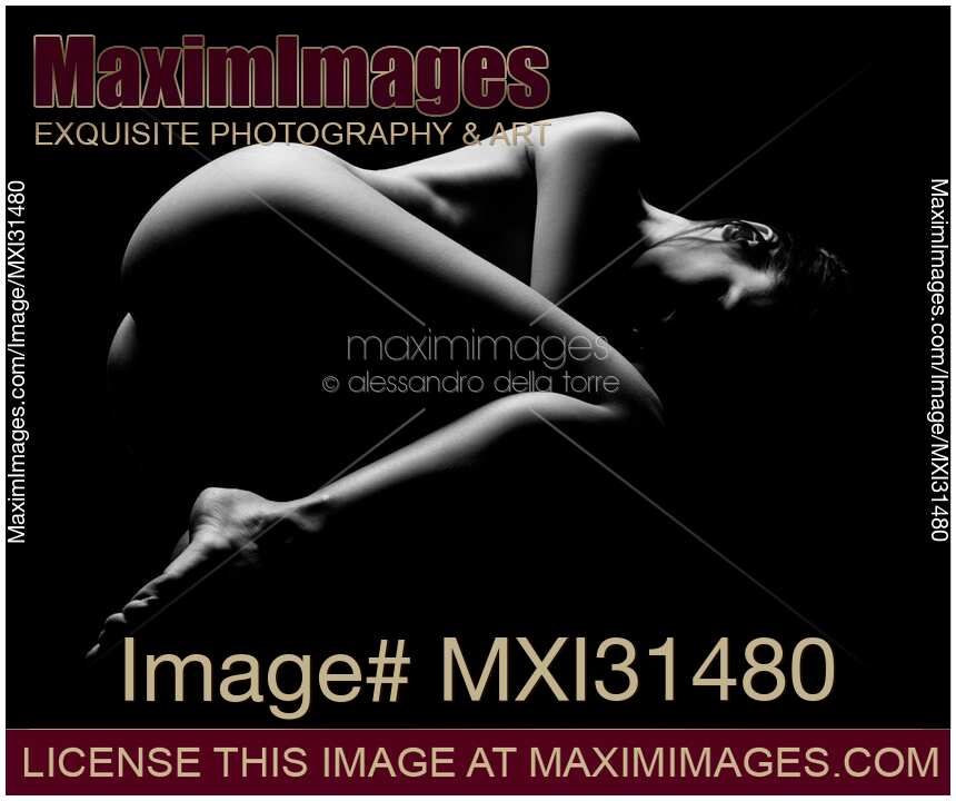 Artistic nude dramatic black and white photo of a woman lying curled