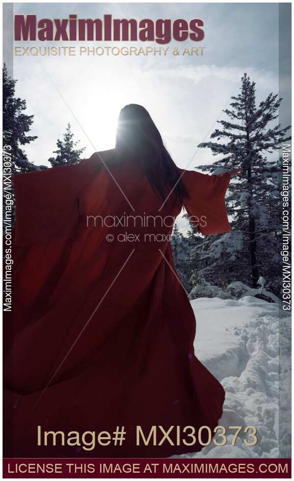 Artistic photo of a beautiful asian woman in red undone kimono running in the snow