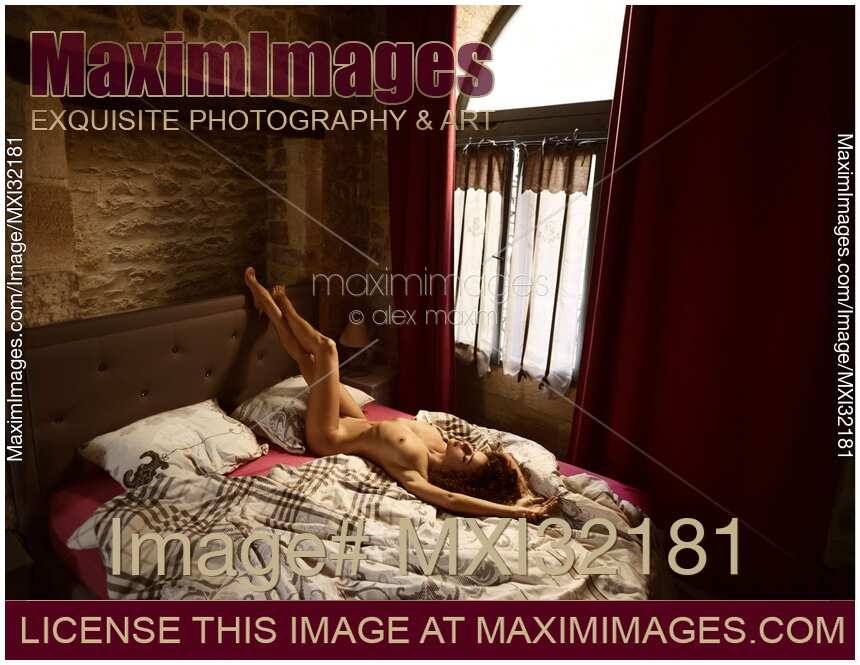Artistic sensual portrait of a sexy nude woman lying on a bed in a dim French bedroom by a window