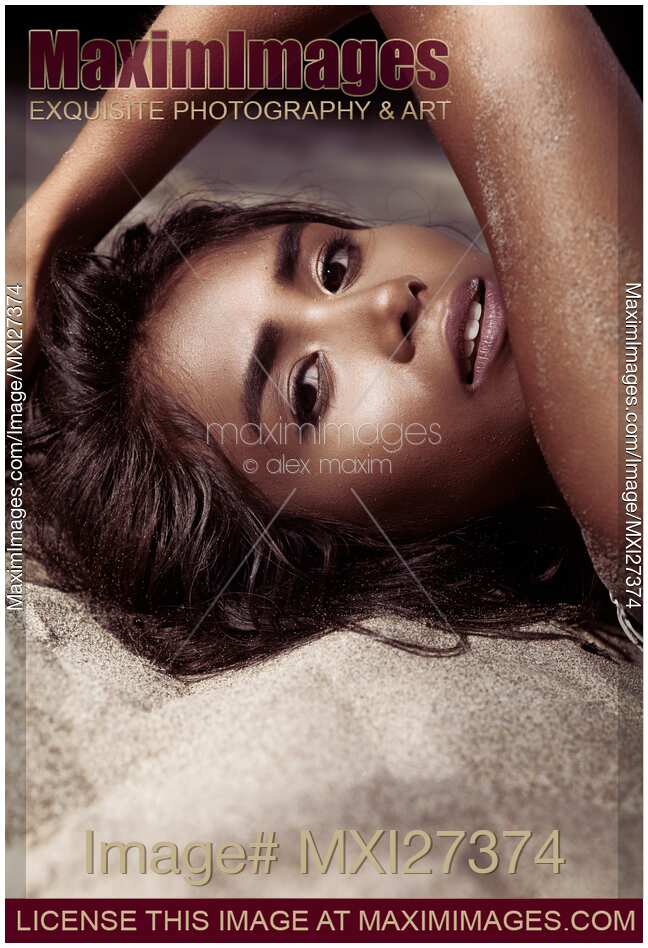Artistic sensual portrait of young woman lying on sand