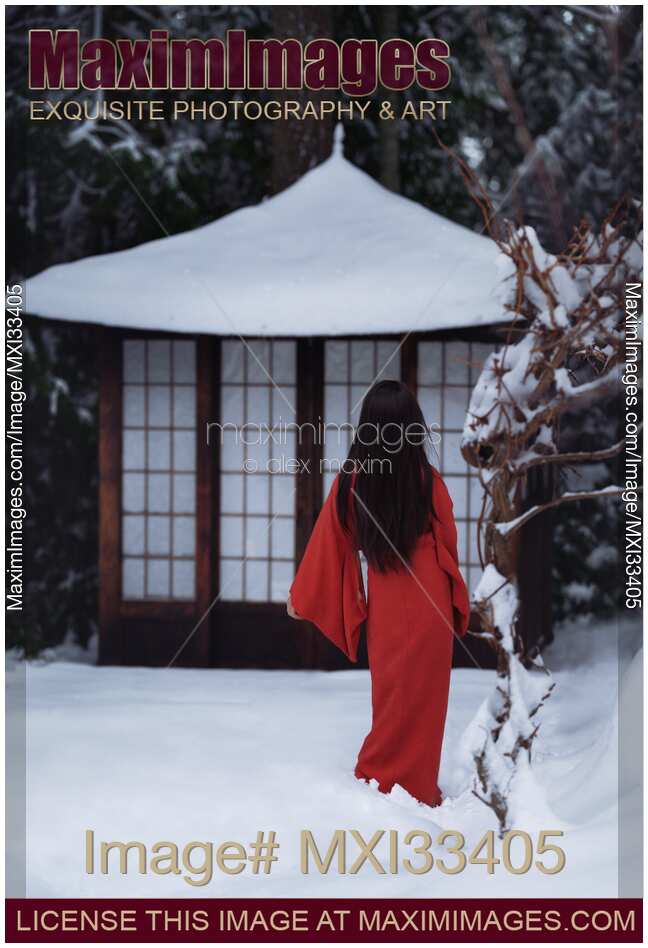 Asian woman in red kimono walking in snow towards little traditional Japanese house or gazebo