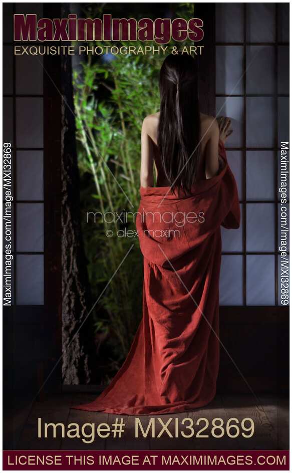 Asian woman in undone red kimono with long hair standing by a shoji door of a Japanese house
