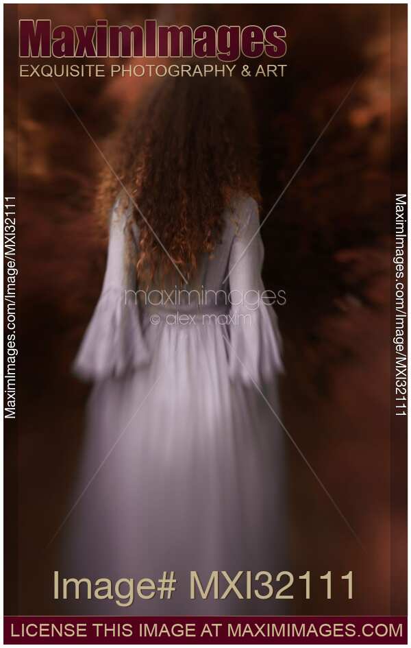 Back of a woman in long dress entering red autumn forest