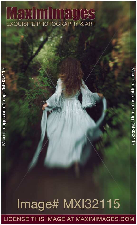 Back of a woman in long vintage dress running away into the forest