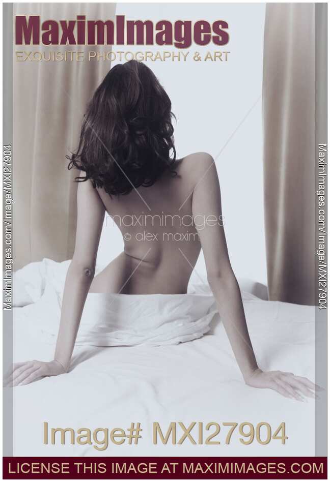 Back of a young woman sitting nude on bed