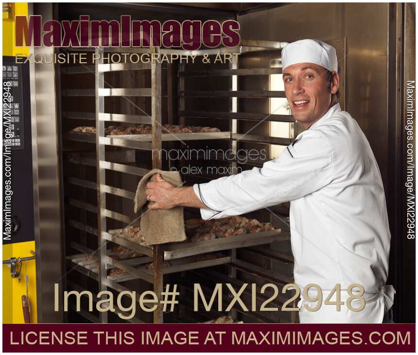 Baker Taking a Rack Trolley out of a Bakery's Oven