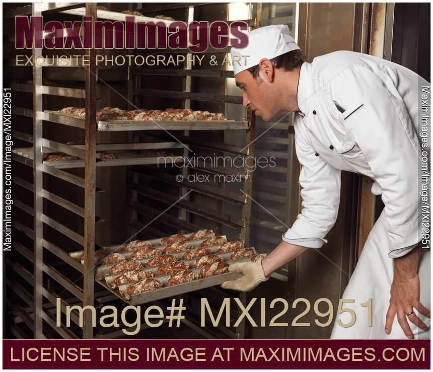 Baker Taking a Rack Trolley out of a Bakery's Oven