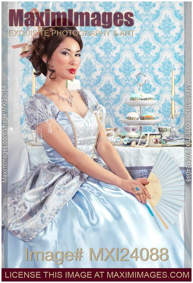 Beautiful asian lady sitting with a fan at a table
