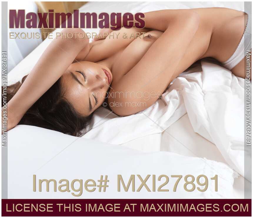 Beautiful asian woman lying on white bed sheets