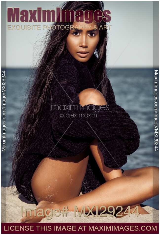 Beautiful asian woman with long black hair at the beach wearing a sweater