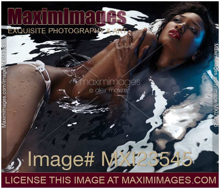 Beautiful black african american woman lying in dark water half naked