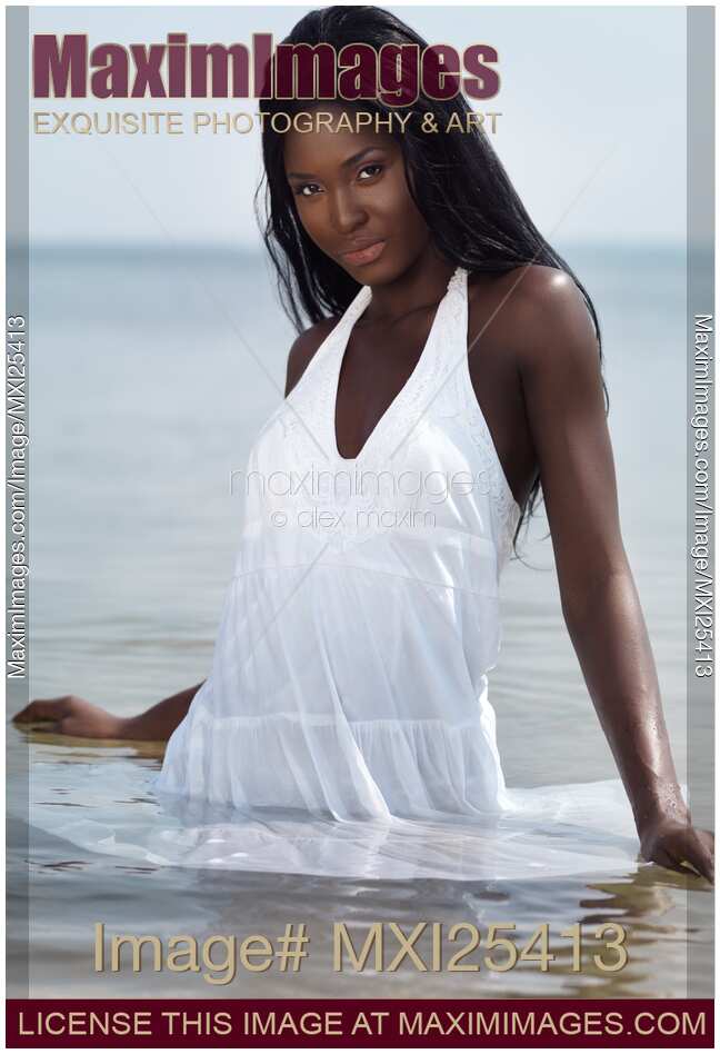 Beautiful black woman in dress standing in water