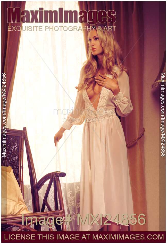 Beautiful blond woman in night gown by the window