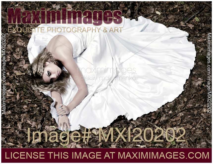 Beautiful Bride in Wedding Gown Lying on Fallen Autumn Leaves