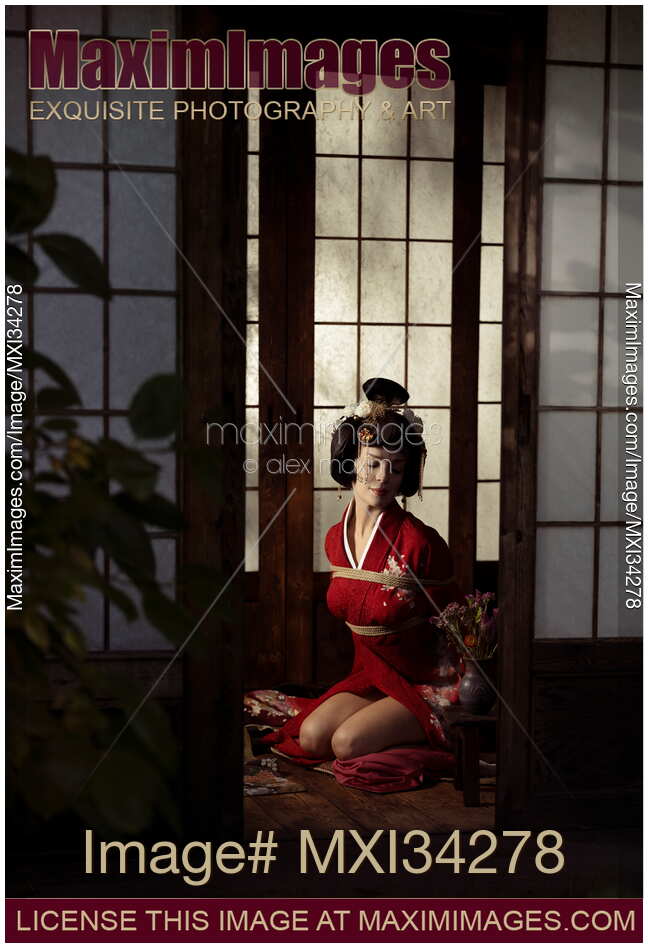 Beautiful caucasian lady, Japanese geisha in red kimono sitting tied up with Shibari bondage ropes