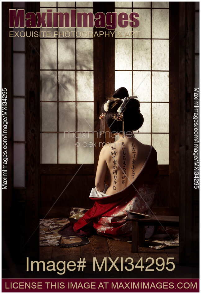 Beautiful geisha sitting in undone red kimono revealing her bare back with japanese calligraphy