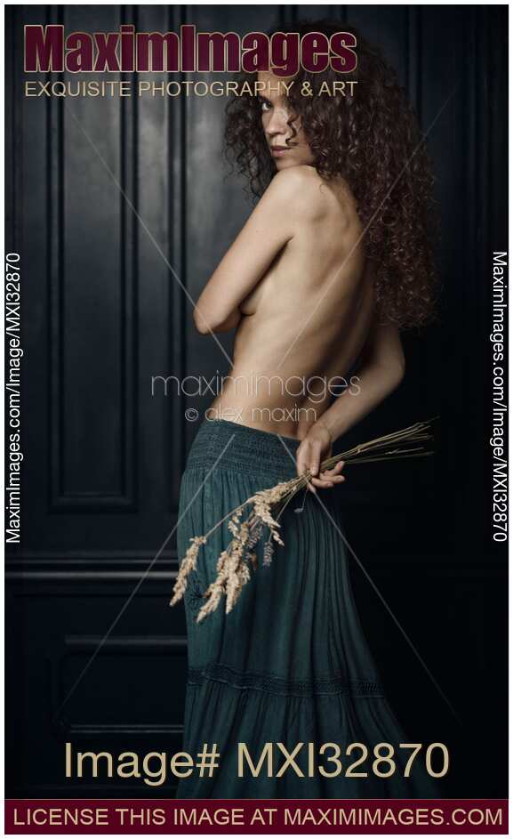 Beautiful girl with bushy curly hair standing topless looking over her shoulder fine art portrait
