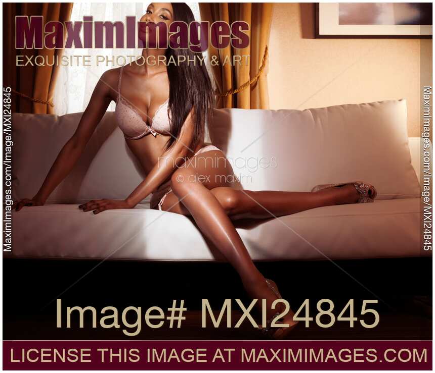 Beautiful glamorous black woman in lingerie sitting on sofa