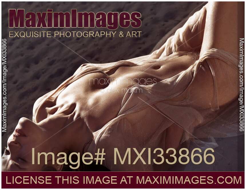 Beautiful half-naked woman lying in sea water her naked sensual sun-tanned body barely covered with sheer clothes