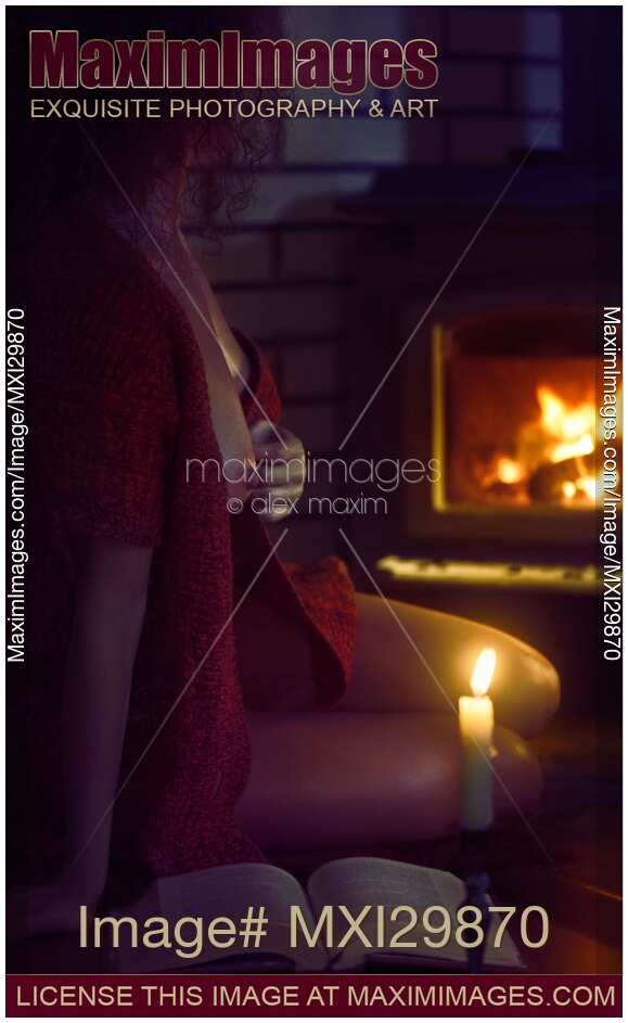 Beautiful half naked woman sitting by the fire with a book