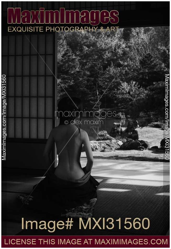 Beautiful half nude asian woman in a Japanese house room with her kimono lowered revealing her naked back