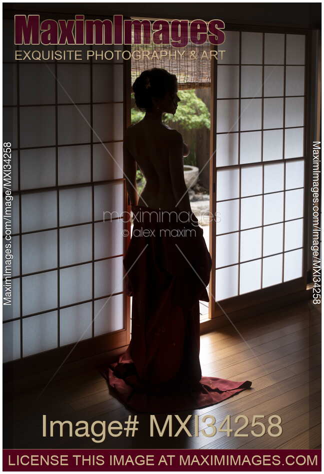 Beautiful half-nude woman with bared back standing by open shoji door of Japanese house with Zen garden