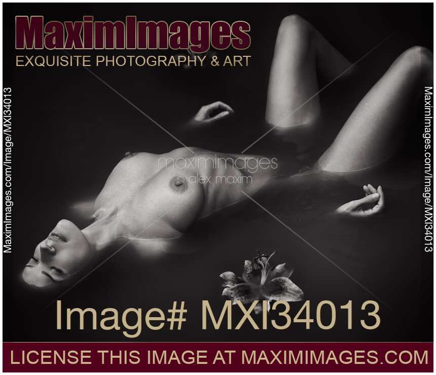 Beautiful naked woman lying half submerged in black water abstract fine art nude black and white