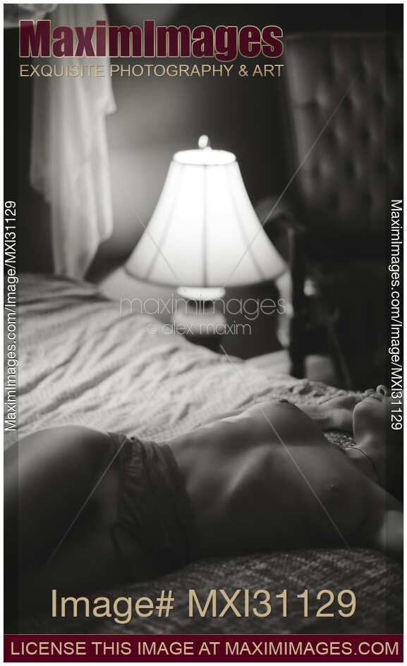 Beautiful naked woman lying on bed in dim light night lamp Candid art nude portrait
