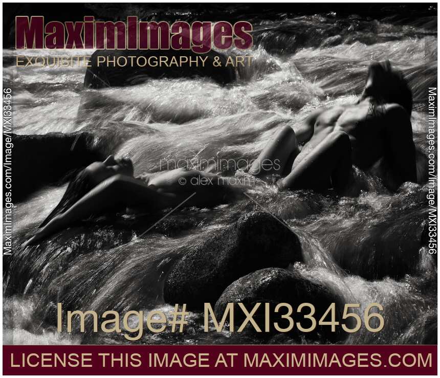 Beautiful nude couple making love in wild water of a mountain river in dramatic black and white nature scenery