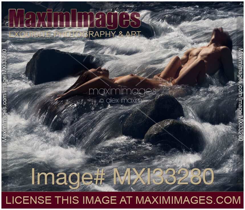 Beautiful nude couple making love lying in wild water of a mountain river in dramatic nature scenery