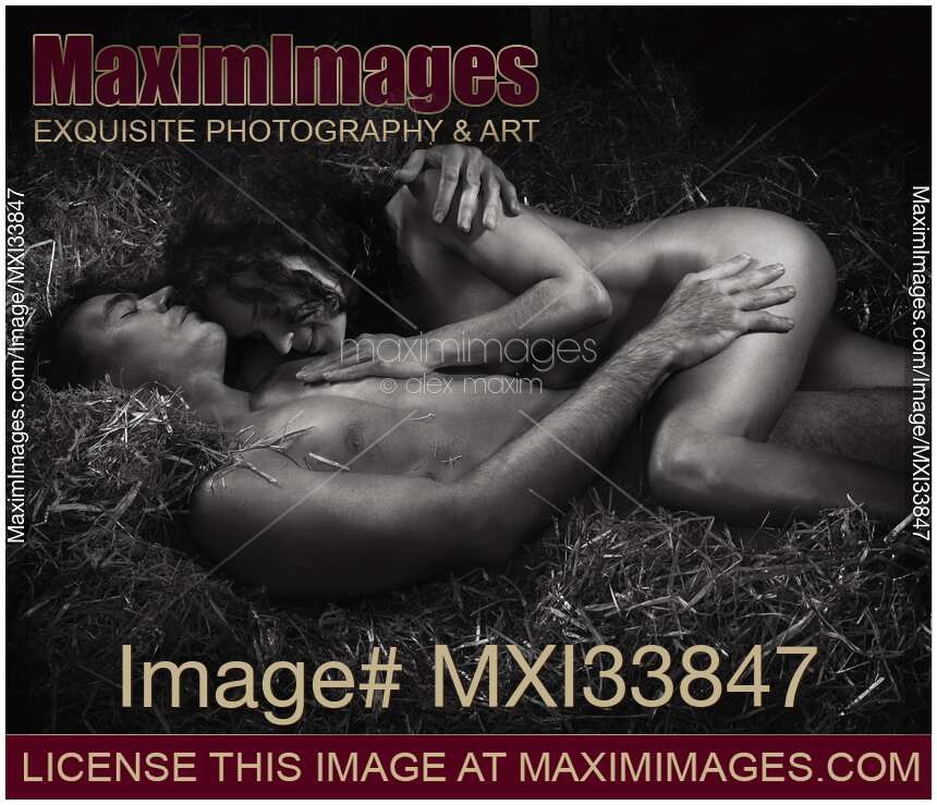 Beautiful nude couple, man and woman, lying relaxed naked sleeping in embrace on straw. Black and white photograph.