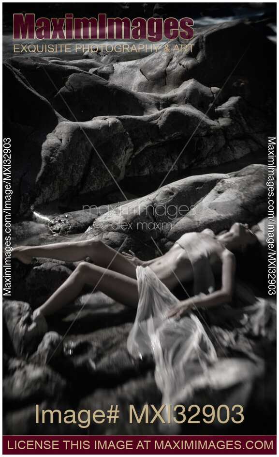 Beautiful nude woman lying by a river her naked body blending with rocky landscape Black and white fine art nudes