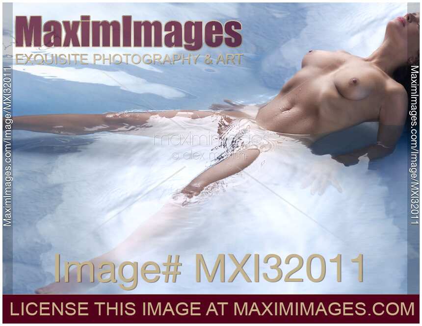 Beautiful nude woman lying in reflective water with her chest arching and her legs wide apart