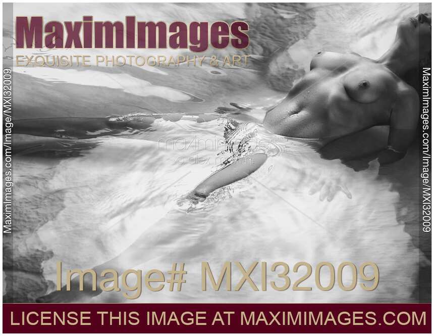 Beautiful nude woman lying in shiny water with her chest arched up and her legs apart Black and white
