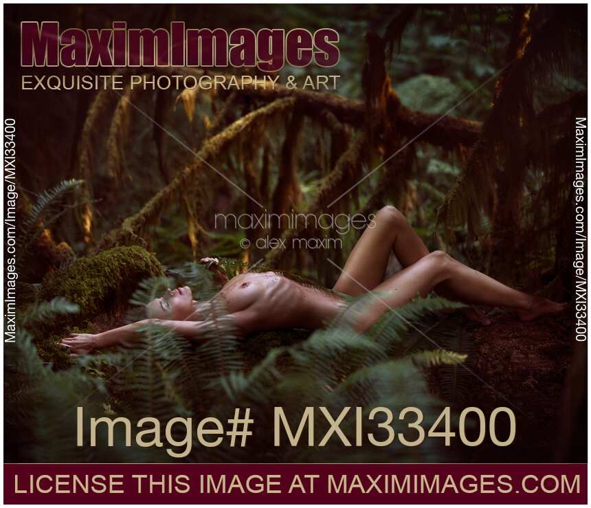 Beautiful nude woman lying on a fallen tree in a mossy green rain forest nature scenery