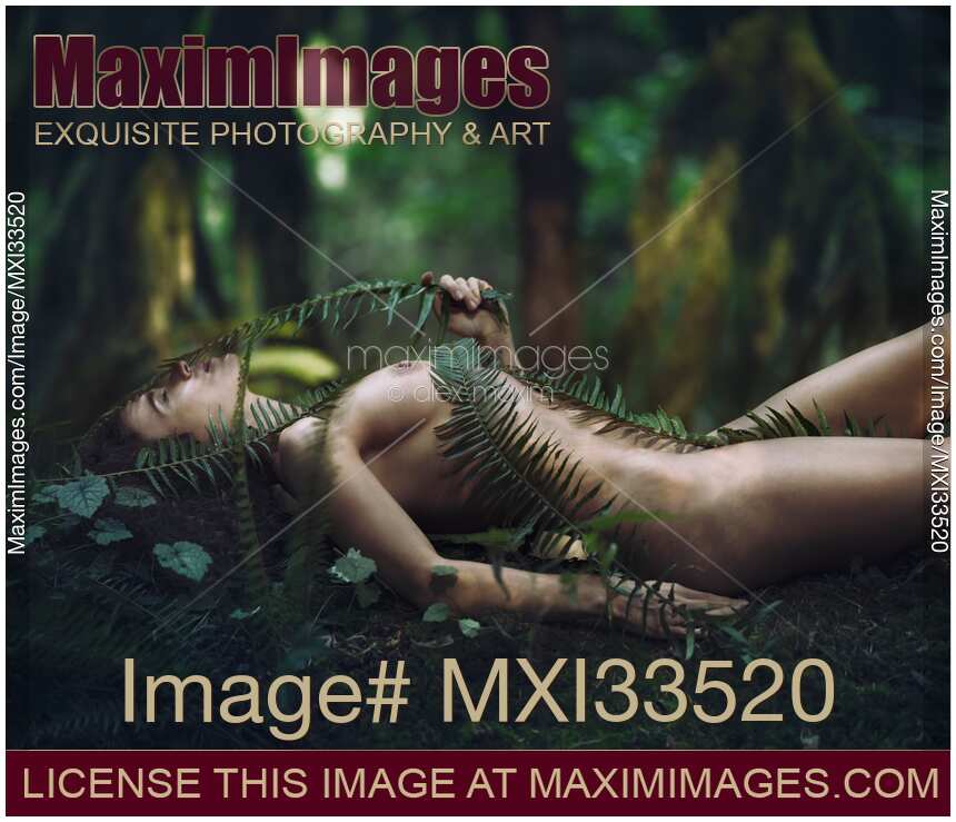 Beautiful nude woman lying on green moss in a rain forest covering her naked body with fern branches Shinrin-Yoku