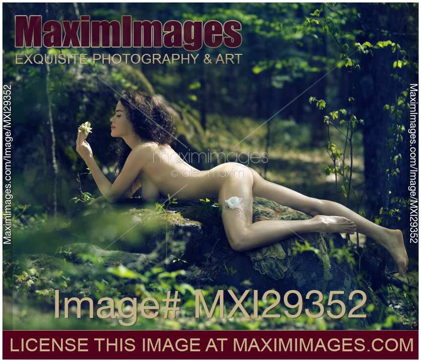 Beautiful nude woman lying on rocks in the nature bathing naked in sunshine