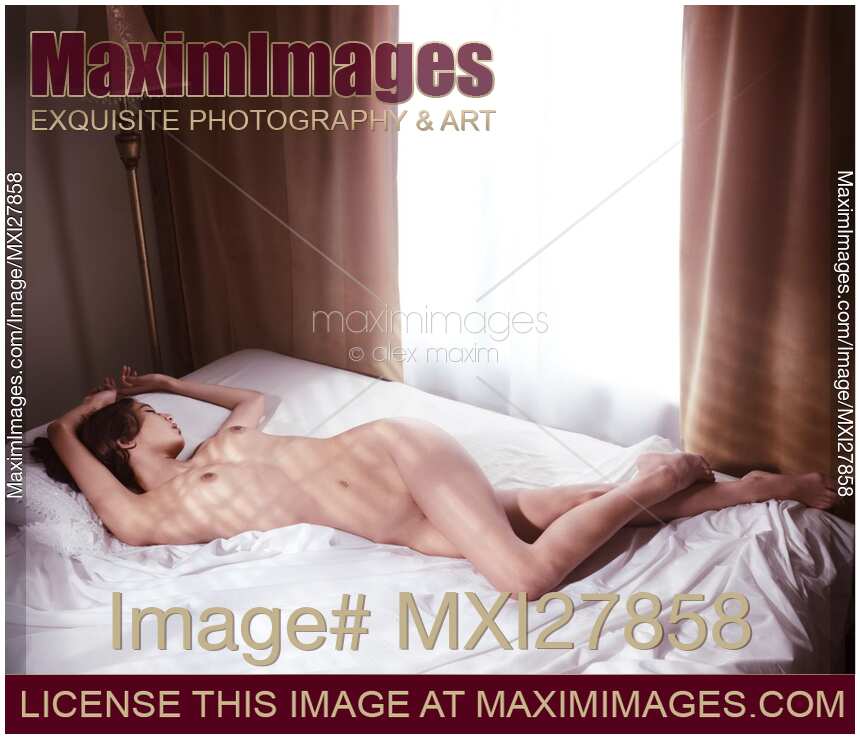 Beautiful nude woman sleeping in bed by the window