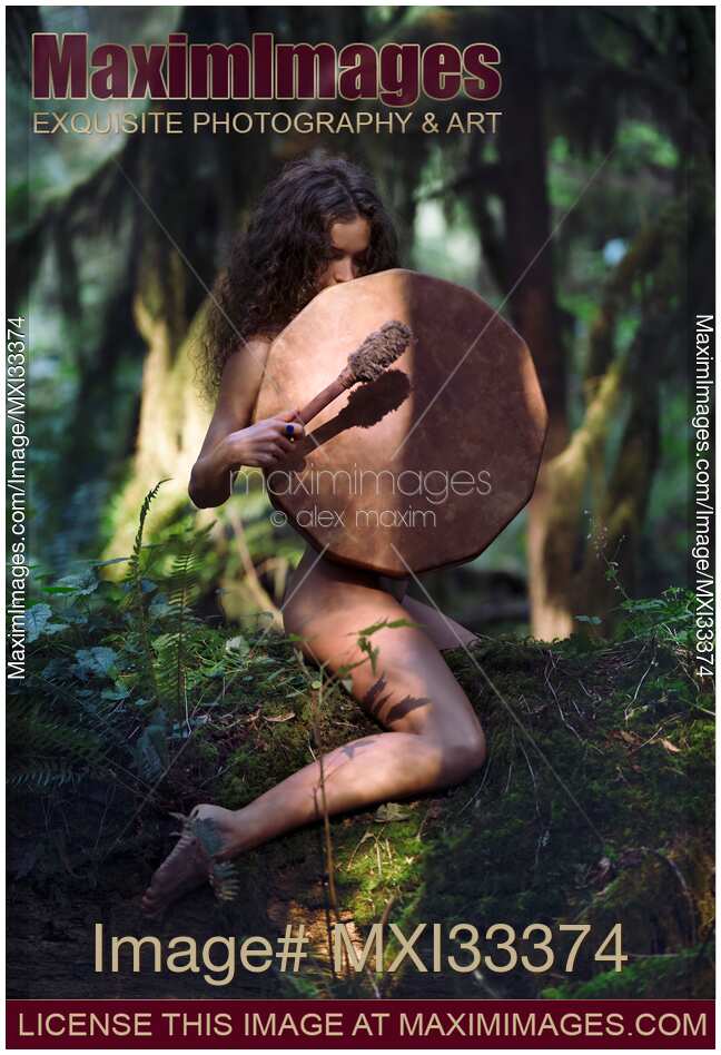 Beautiful nude woman with a shamanic drum in a tranquil dark forest scenery