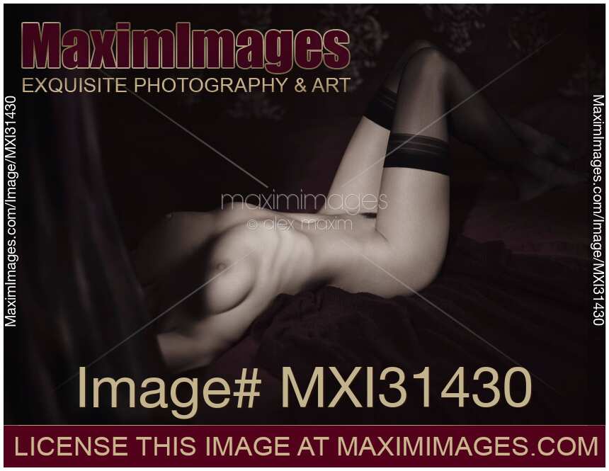 Beautiful nude woman with sensual body in black stockings lying in bed Fine art nude photography