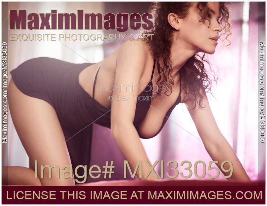 Beautiful seductive woman in a sensual prowling pose wearing a sexy black dress