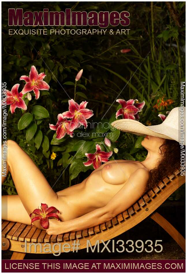 Beautiful seductive woman with wet naked sun-tanned body lying topless on a chaise in sun hat